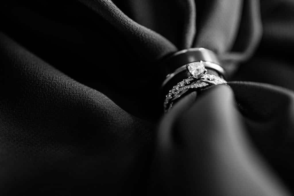 black and white photo of wedding rings on a bed of silk, photo from Weddings By Ray