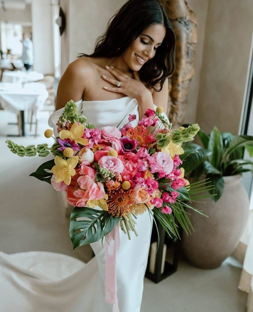 bride with pink and yellow tropical bouquet from In Bloom Florist