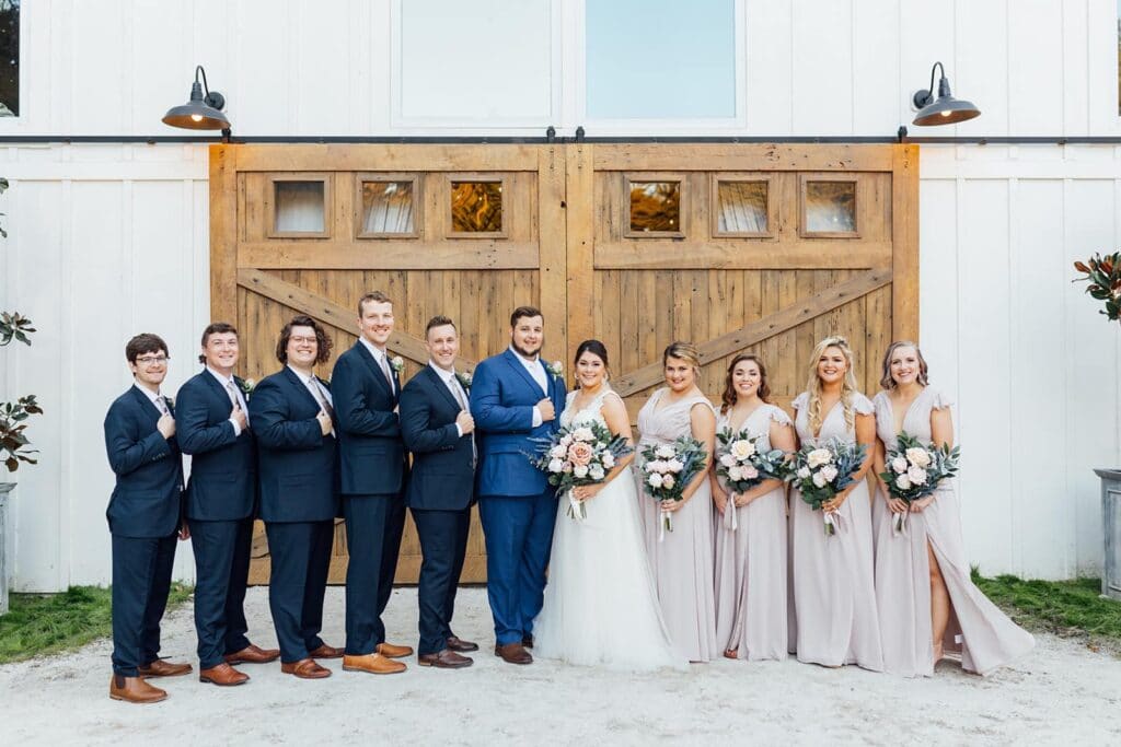 wedding party with silk bouquet and silk boutonnieres from Wedding Day Flower Rental in front of large wooden sliding barn doors