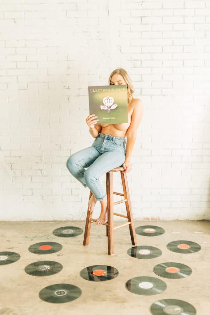 topless woman posing behind album cover with LPs on the floor by Sydney Morman Boudoir Photography