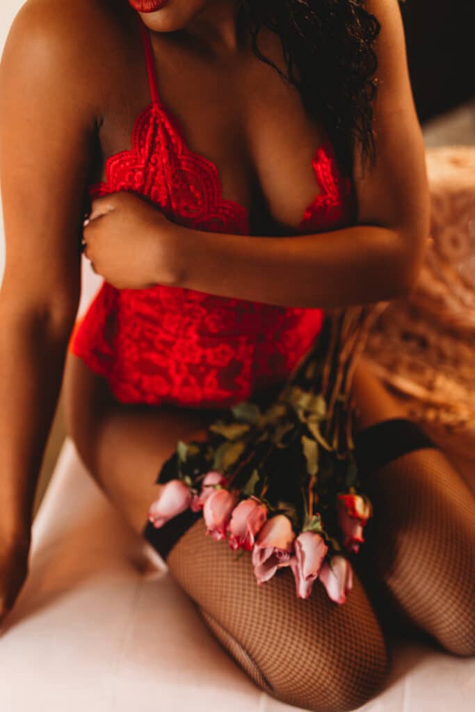 woman in red teddy with pink roses kneeling by Sydney Morman Boudoir Photography