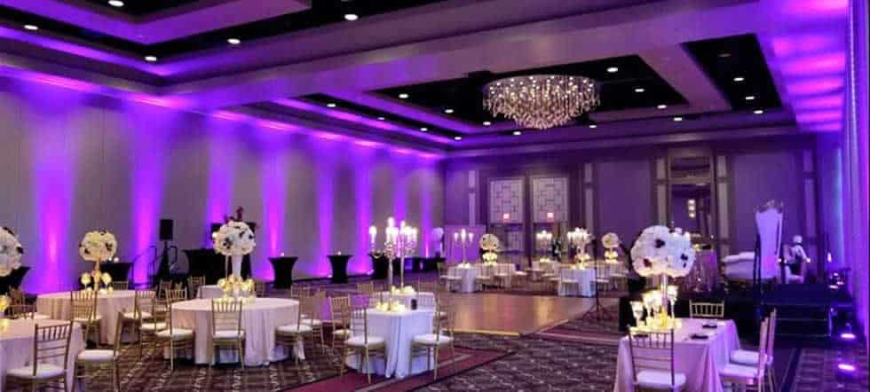 wedding reception room with colored up lights and tall centerpieces from Party Springs Entertainment