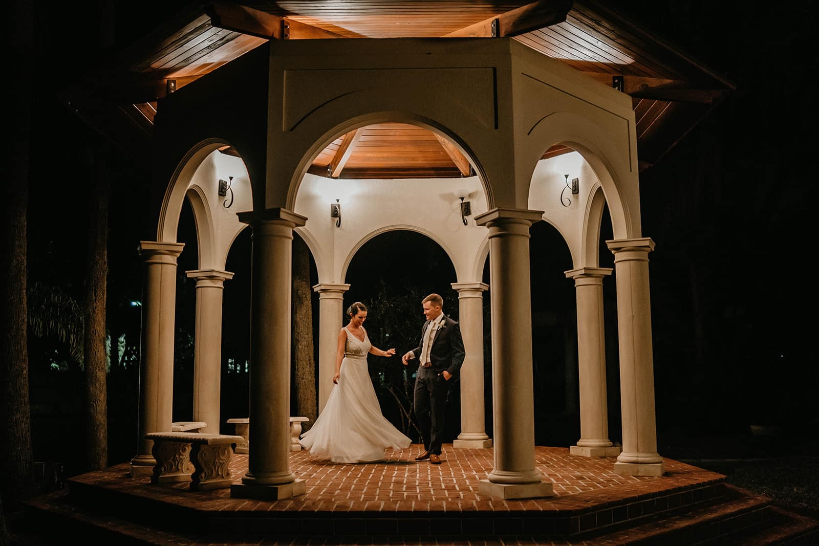 couple on wedding day at night in well lit gazebo holding hands