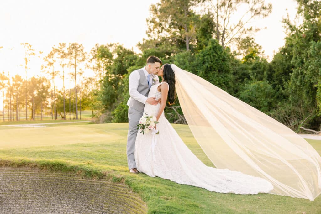 bride and groom kissing as the sunsets on a golf course