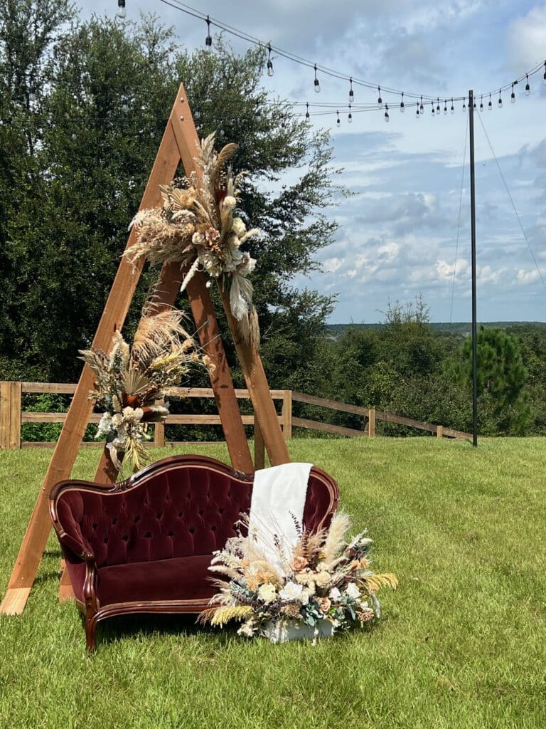 sofa at outdoor sitting area with wooden arch, market lights and autumnal flowers at The Carriage House at Vedder Farms