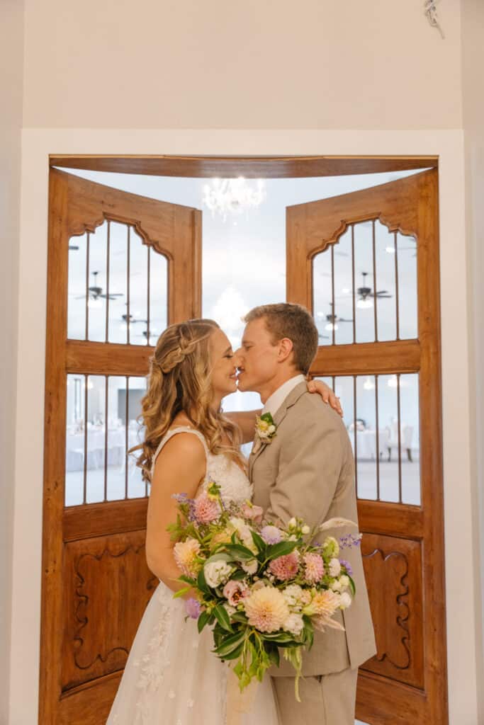 bride and groom kissing in front of tall wooden door at The Carriage House at Vedder Farms