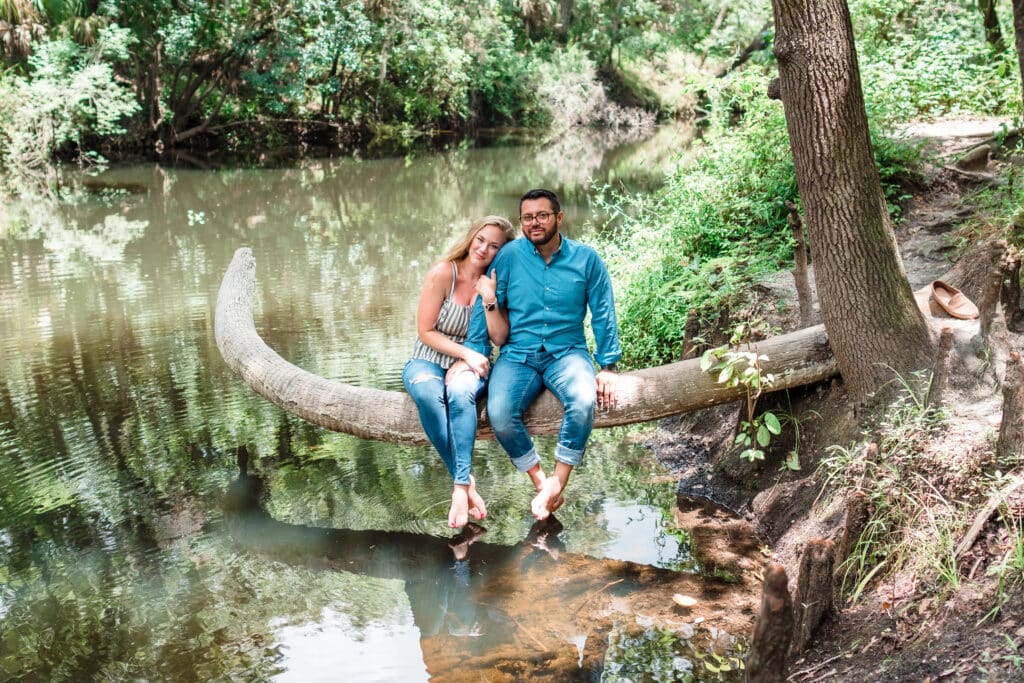 couple in jeans sitting on a tree over a river photo by Jerzy Nieves Photography LLC