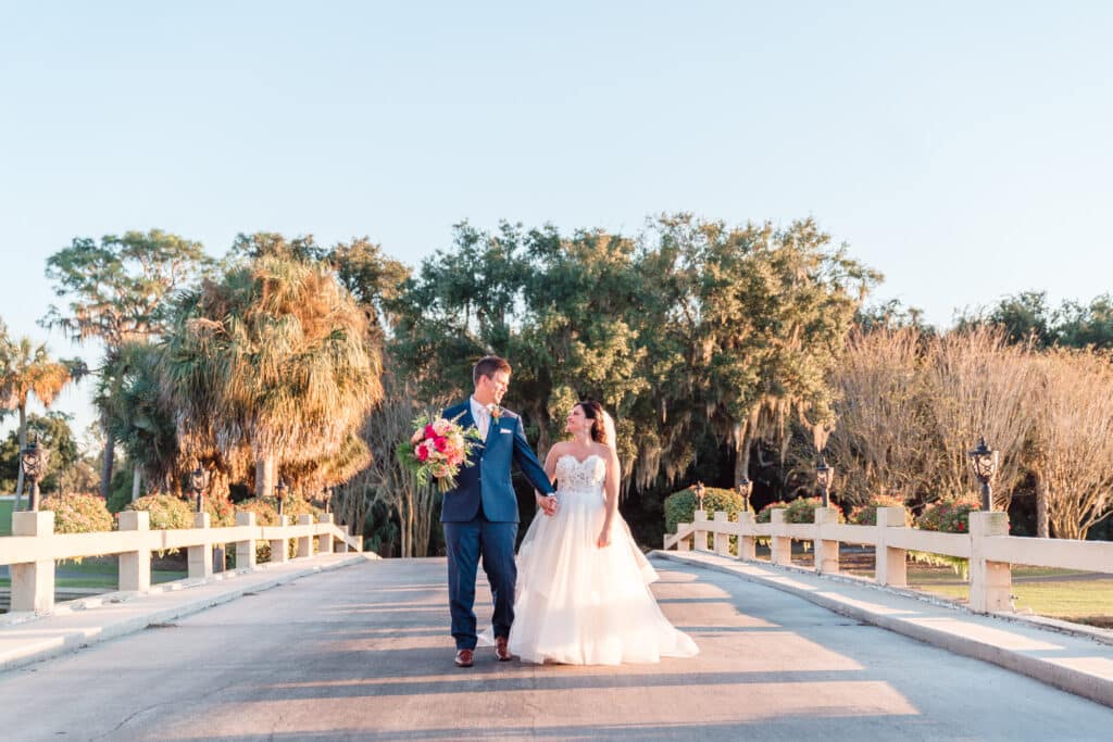 bride and groom holding her bouquet walking across a bridge outdoors photo by Jerzy Nieves Photography LLC