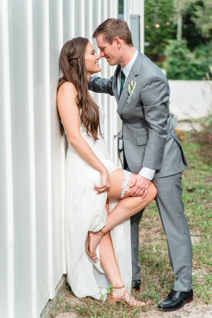 bride leaning against building showing her garter to her groom photo by Jerzy Nieves Photography LLC