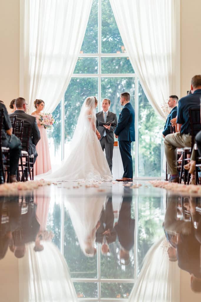bride and groom saying their vows against a large glass window with long white drapes photo by Jerzy Nieves Photography LLC