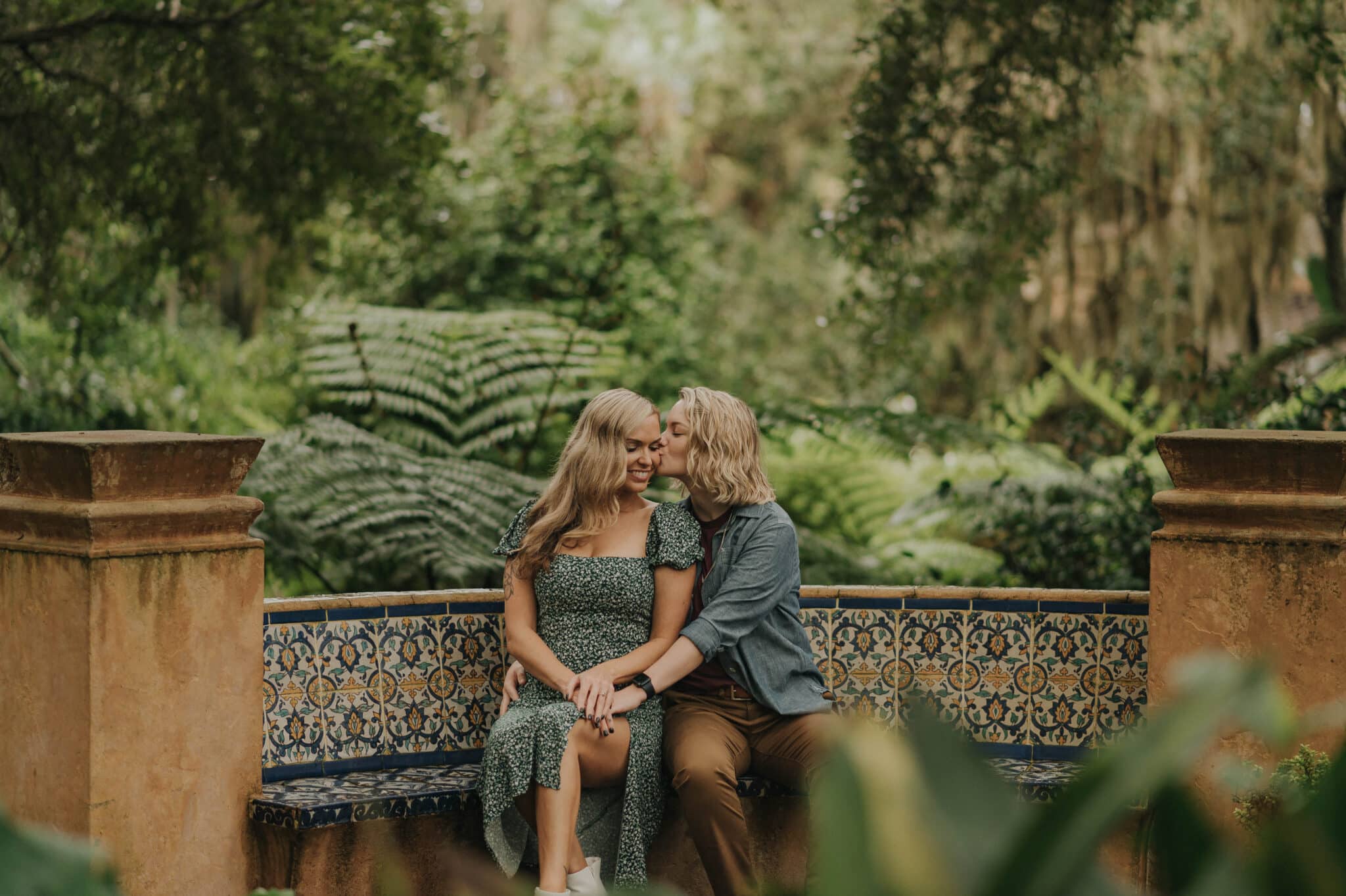 couple sitting together on colorful mosaic bench in tropical background