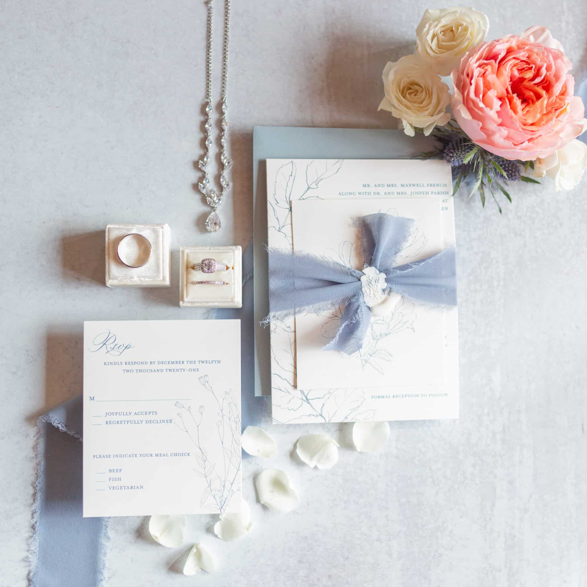 detail shot from dusty blue wedding inspiration with invitation pieces floral and jewelry with wedding rings