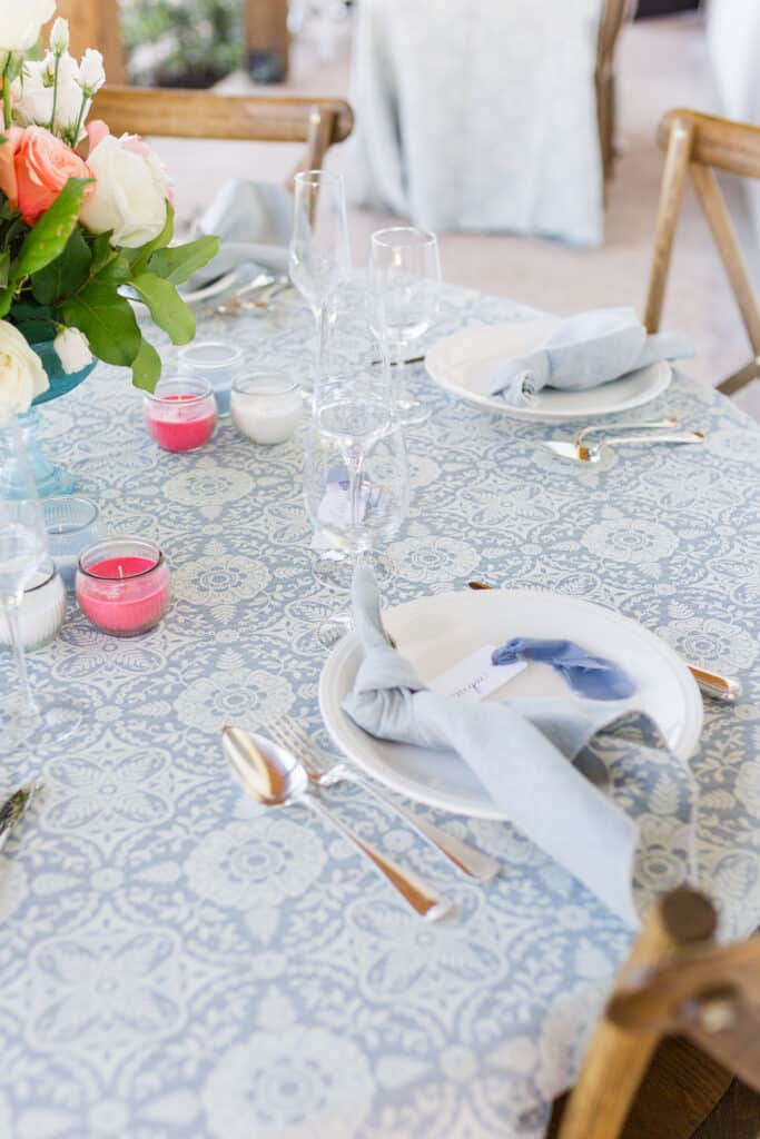 table set for guess at event with lace linen and pink blue and white candles towards the center