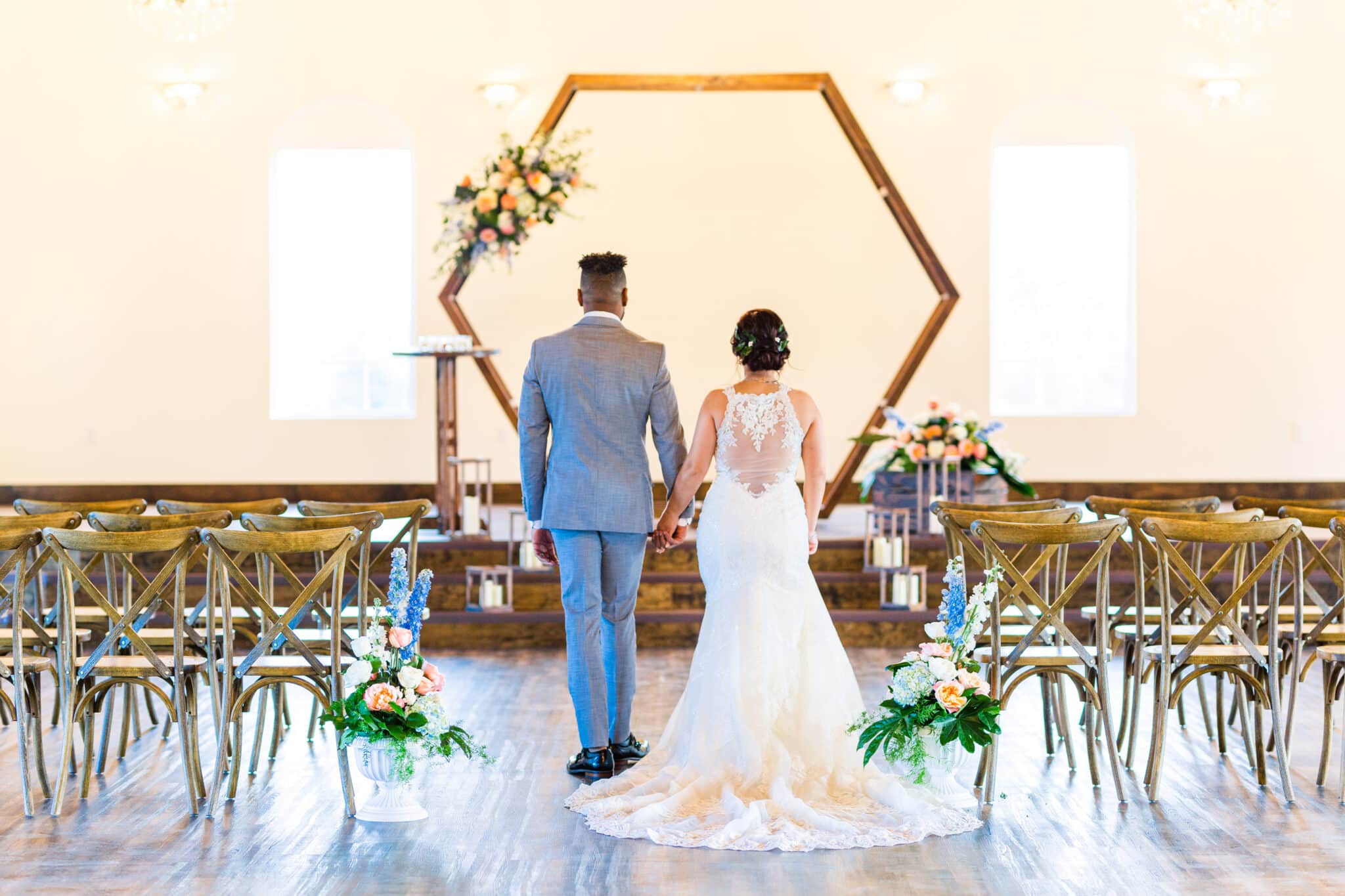 couple walking down aisle of ceremony space in suit and wedding dress