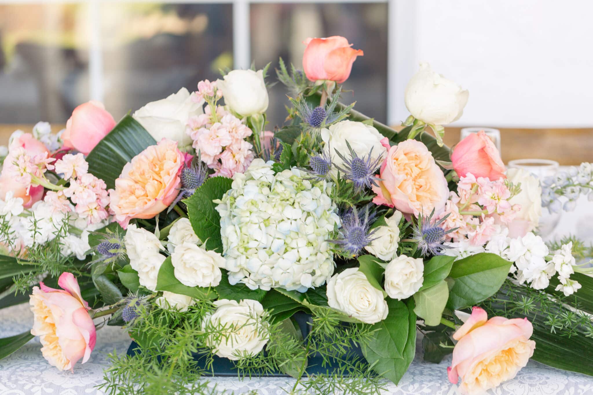 floral piece with coral colored floral and white mixed with greenery