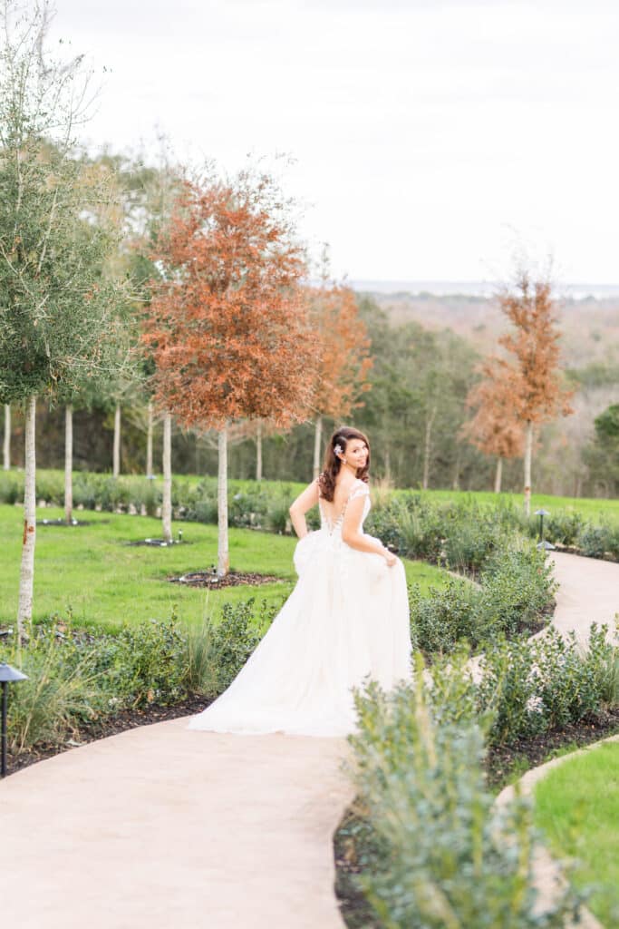 Bride walking down a path looking over her shoulder smiling