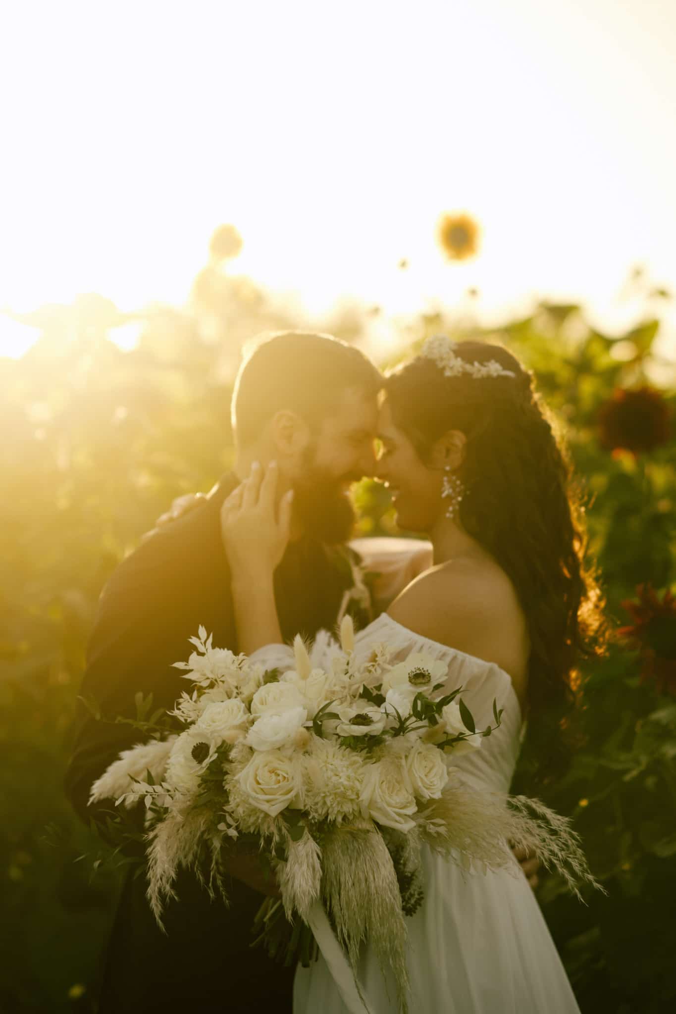 close up image of couple on wedding day touching foreheads and smiling while bouquet is in front of them