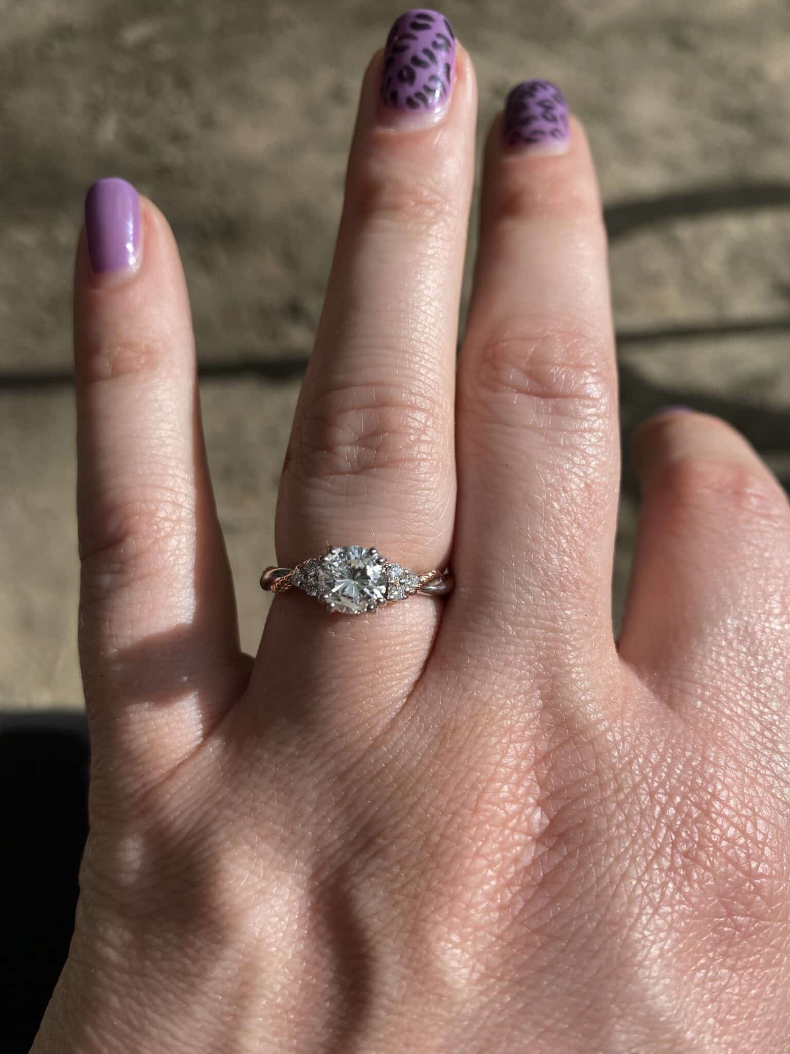 close up image of engagement ring from surprise engagement proposal with purple finger nails