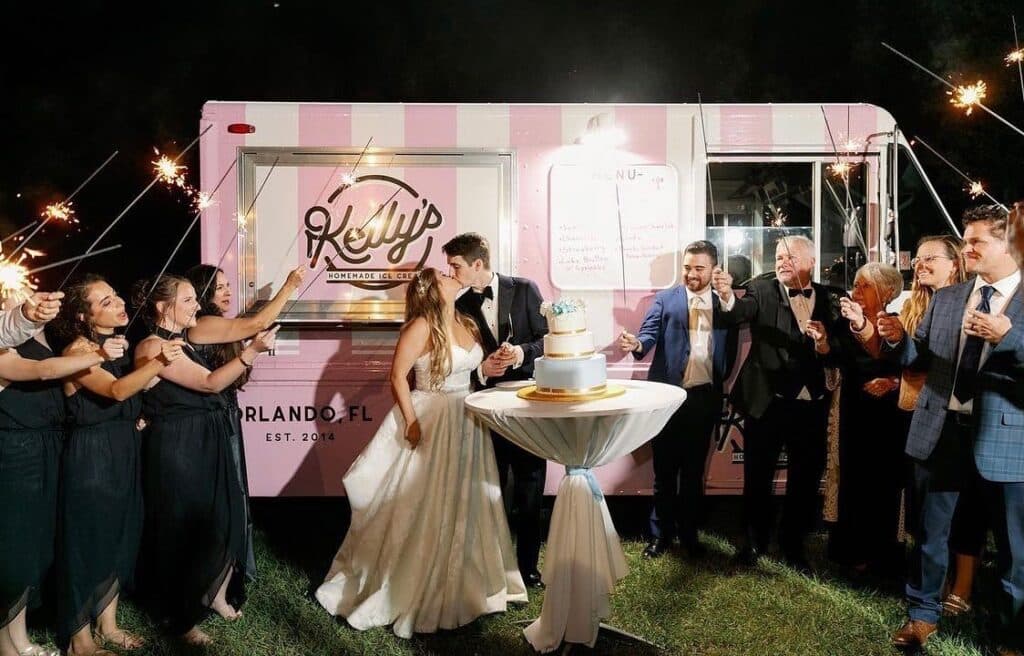 bride and groom kissing and celebrating with wedding party in front of Kelly’s Homemade Ice Cream truck