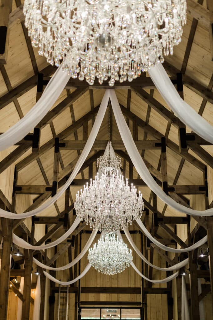 barn ceiling iwth white swags and crystal chandeliers at The Barn at Hidden Oaks Farm of Lake Mary