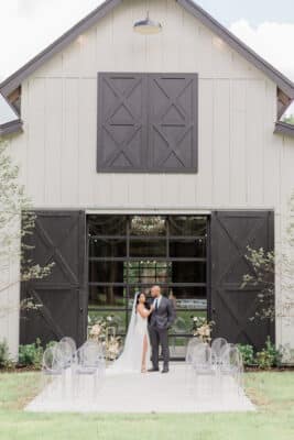 Bride and groom in front of large barn doors at The Barn at Hidden Oaks Farm of Lake Mary