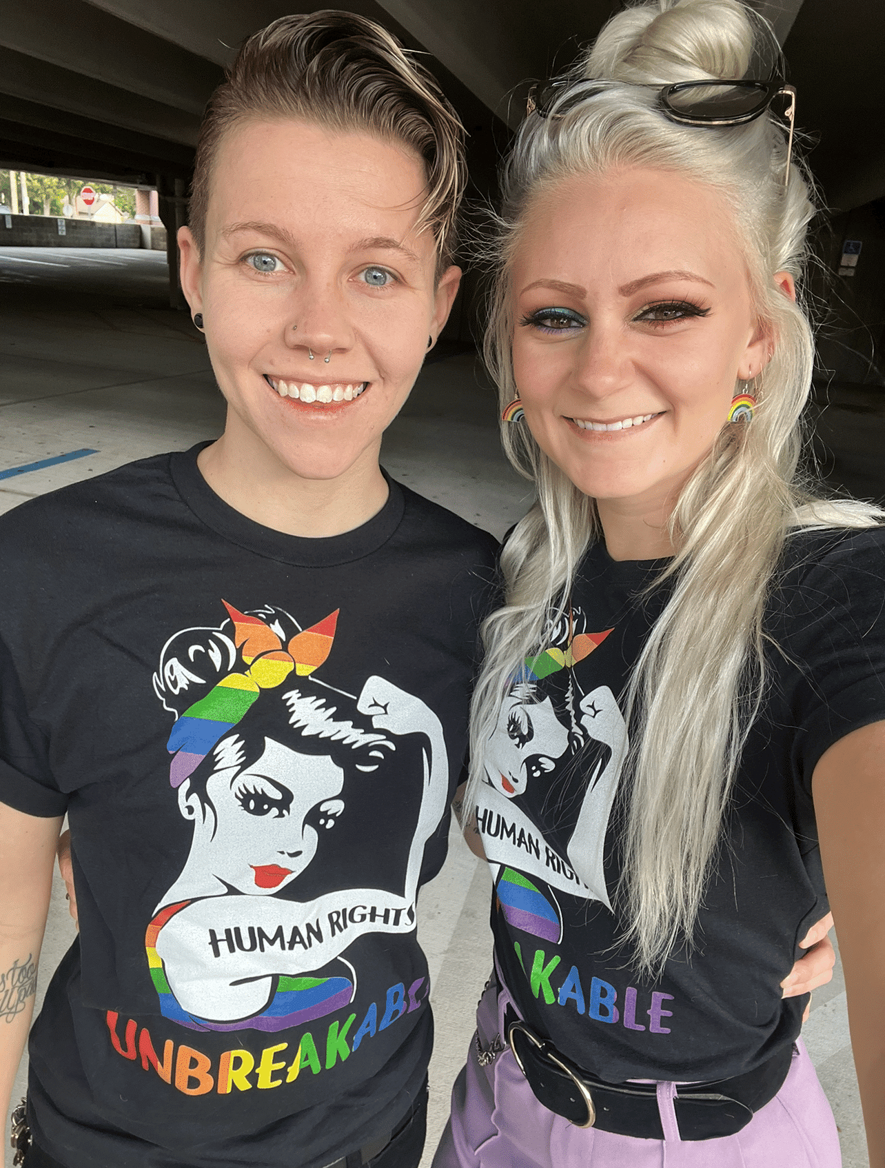 couple wears matching black tshirts with design on them smiling in parking garage