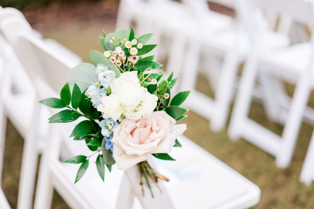 small flower arrangement at end of wedding aisle of white chairs