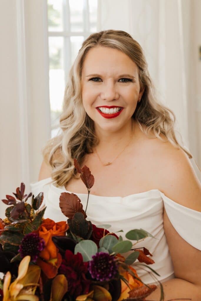 bride with red lipstick holding unique bouquet with autumn colored leaves from Sweet Pea Design Collective