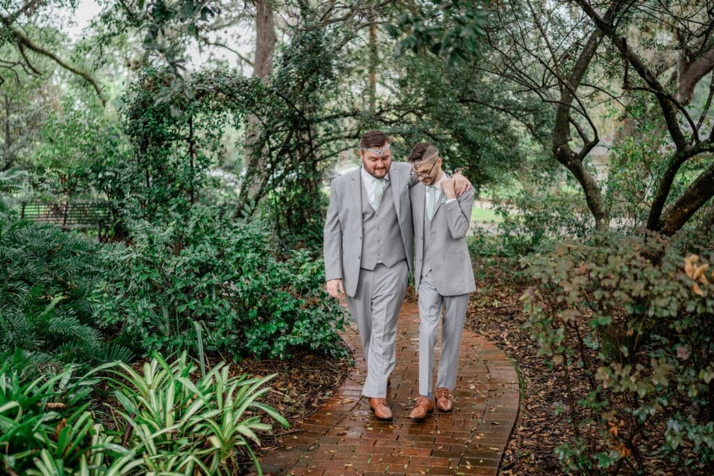 grooms walking on wooded path in grey wedding suits