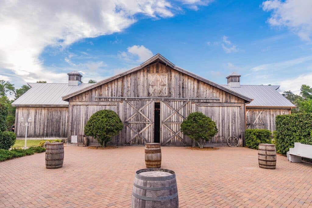 outdoor cocktail hour and reception area with barrel tables and barn at Bending Branch Ranch in New Smyrna Beach, FL