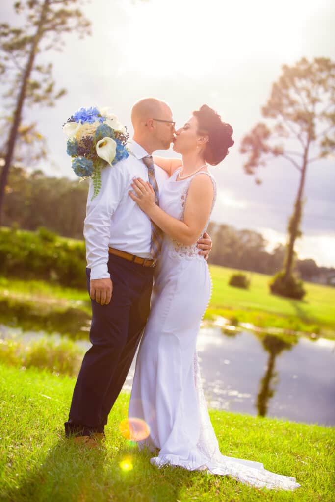 bride adn groom kissing outdoors near lake at the Diamond L Venue in Volusia County, near Deltona, FL