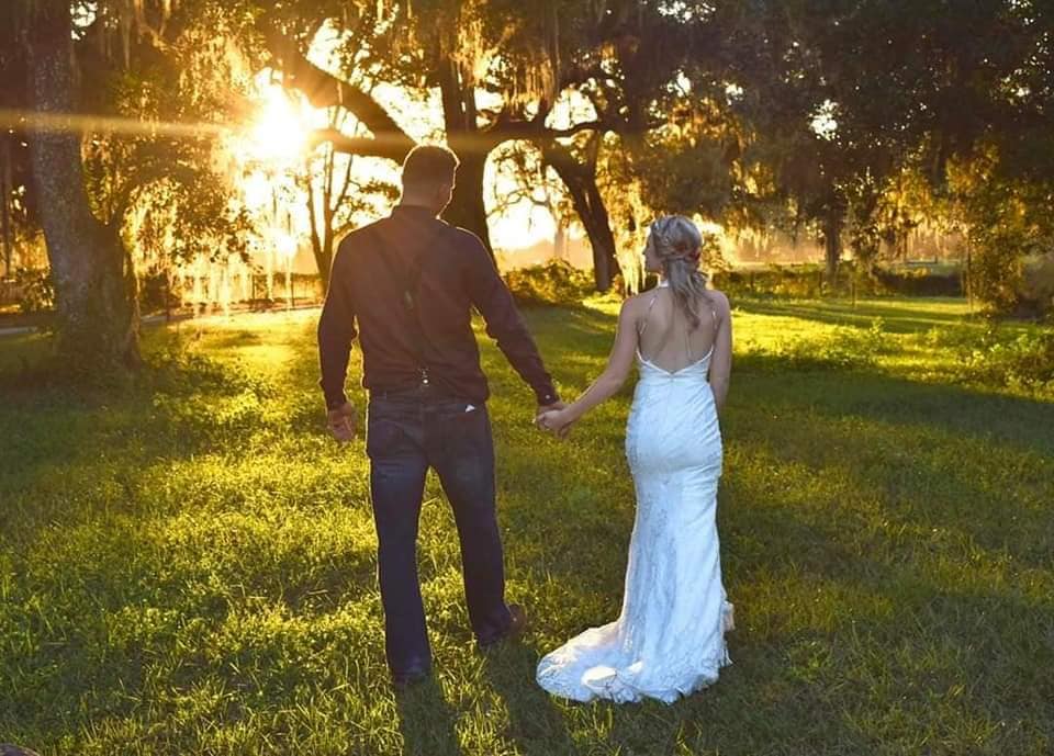 Bride and groom walking hand in hand facing away from the camera towards the sunset