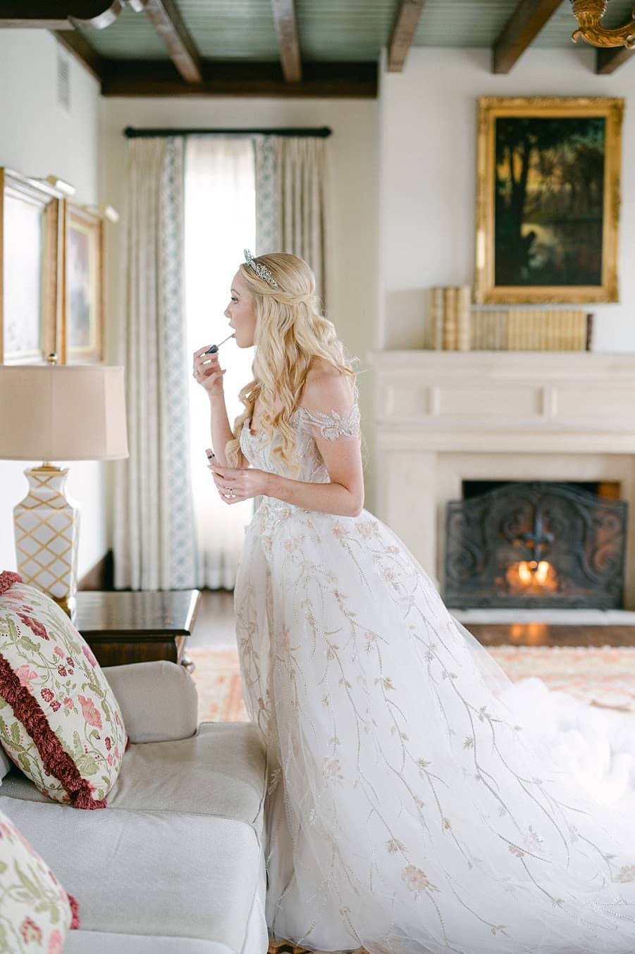 bride putting on lipstick in the mirror