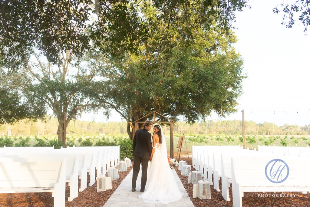 bride and groom walk down aisle of outdoor wedding ceremony before guests arrive at Ever After Farms Citrus Barn