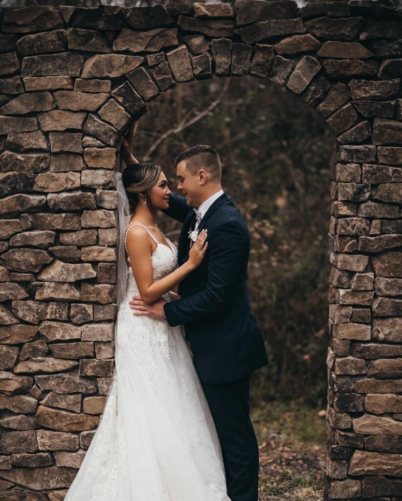 bride and groom sharing a moment against rock wall at October Oaks Farm