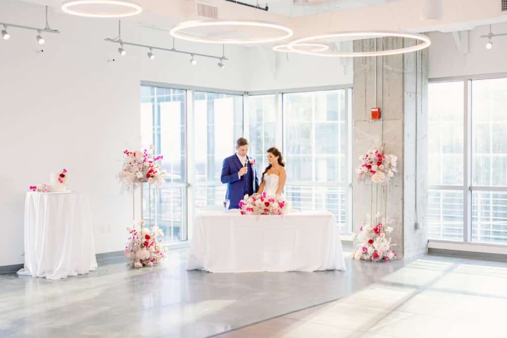 bride and groom in corner of high rise building at cake table with flower arrangements around them at The Balcony Orlando