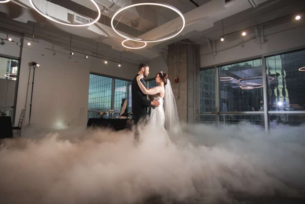 bride and groom dancing on a cloudy dance floor with white circular lights above them as the sun sets at The Balcony Orlando venue