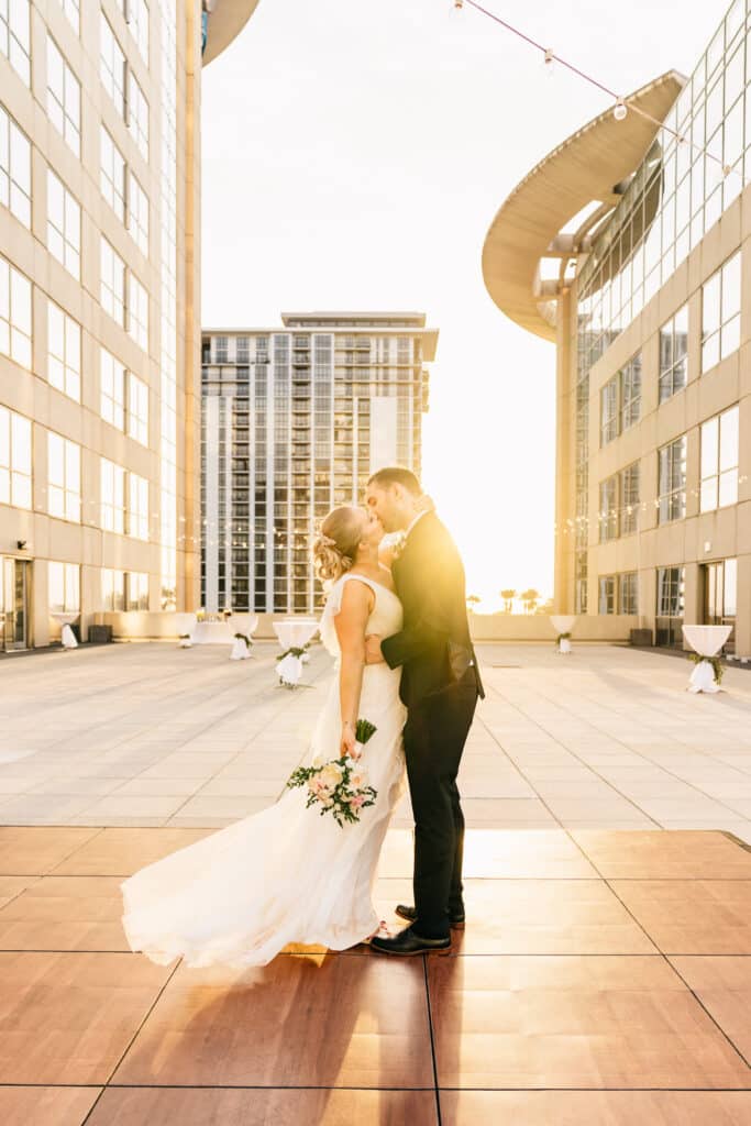 bride and groom kissing as sun sets between buildings at The Balcony Orlando venue