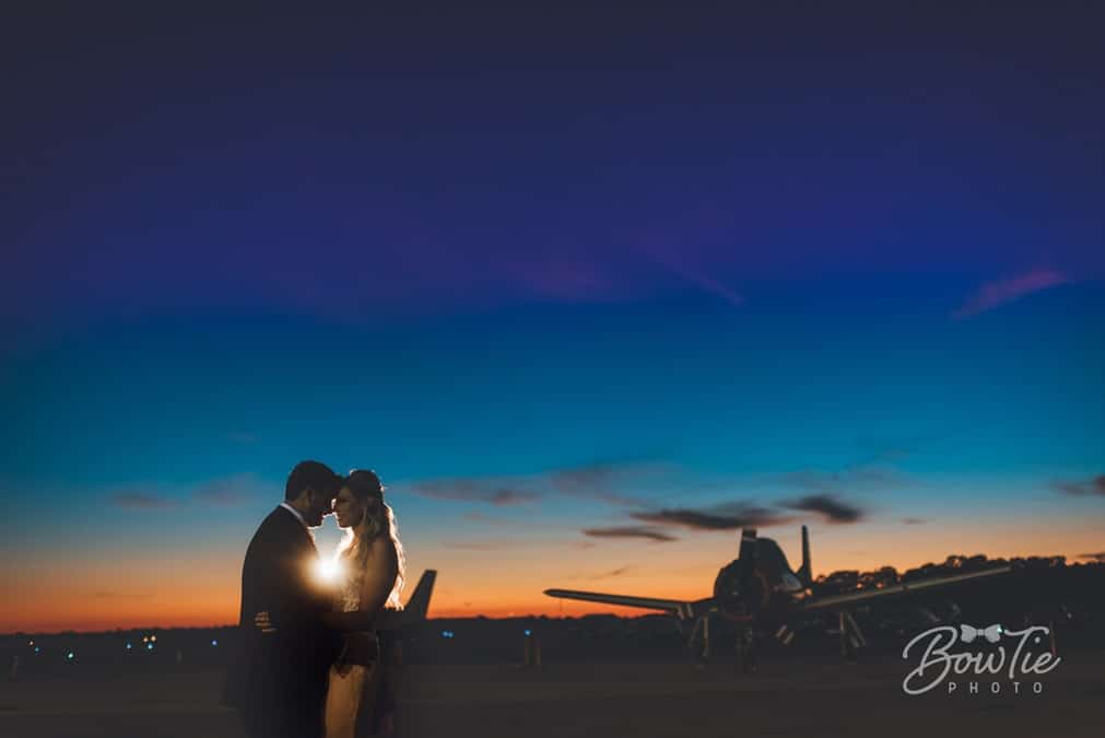 bride and groom kissing as sunsets on them and a plane at The Warbird Air Museum