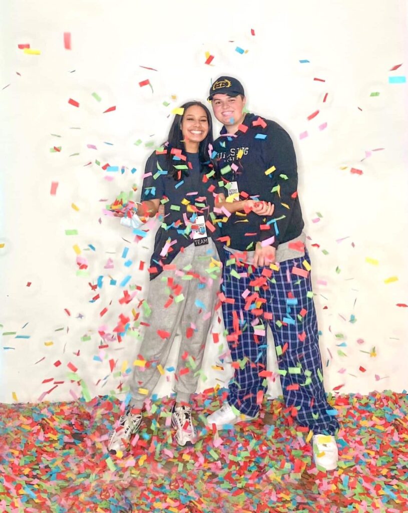 couple stand together with large amounts of confetti floating down around them