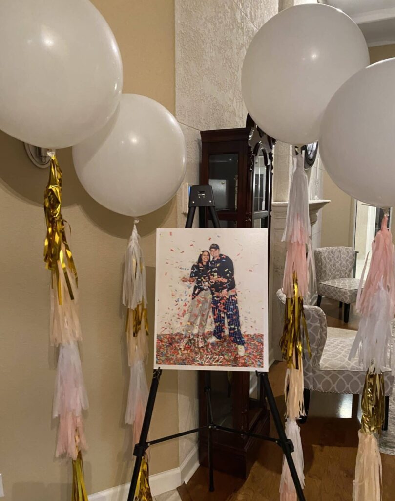 picture of another picture of a couple sitting on an easel surrounded by white balloons with streamer strings attached