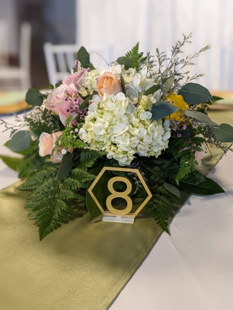 Table number, against hydrangea, and Rose centerpiece coordinated by Events by Rachel