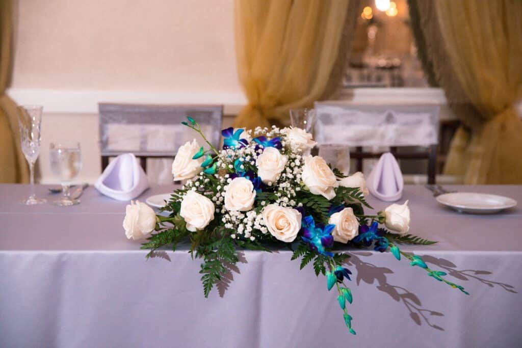 Wedding spray of white roses with teal ribbon at sweetheart table coordinated by Events by Rachel