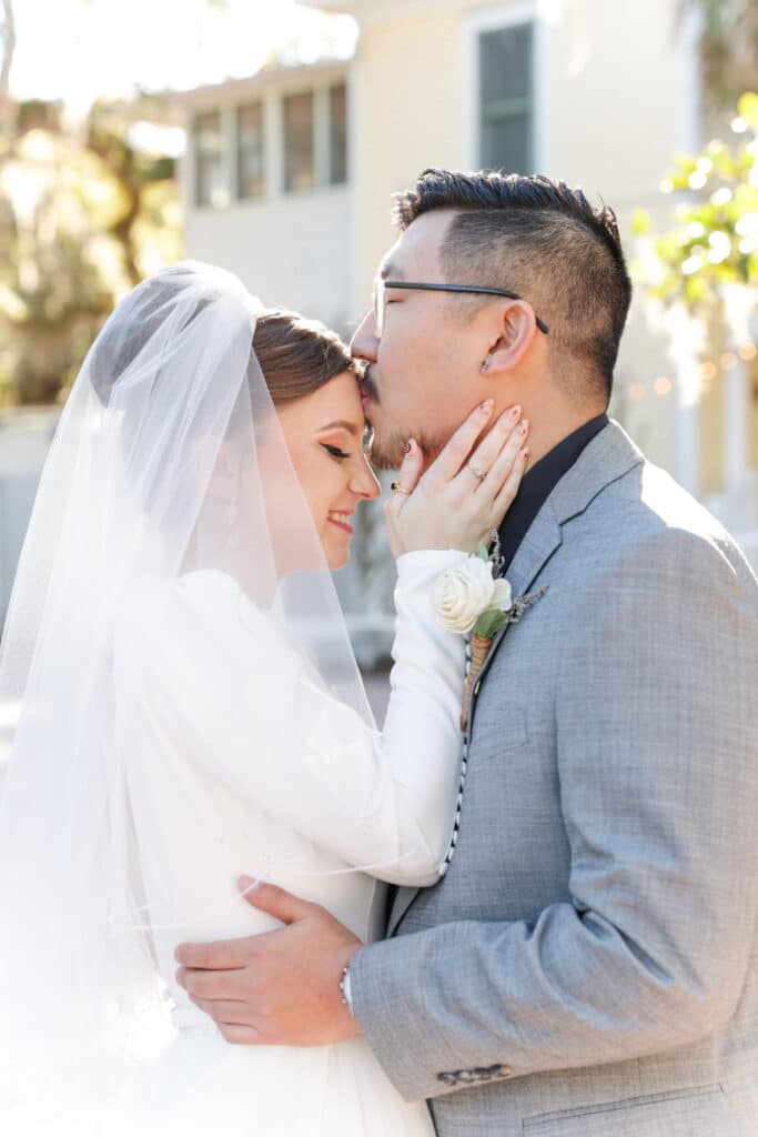 photo of groom kissing bride on the forehead by Sylvia Santos Photography