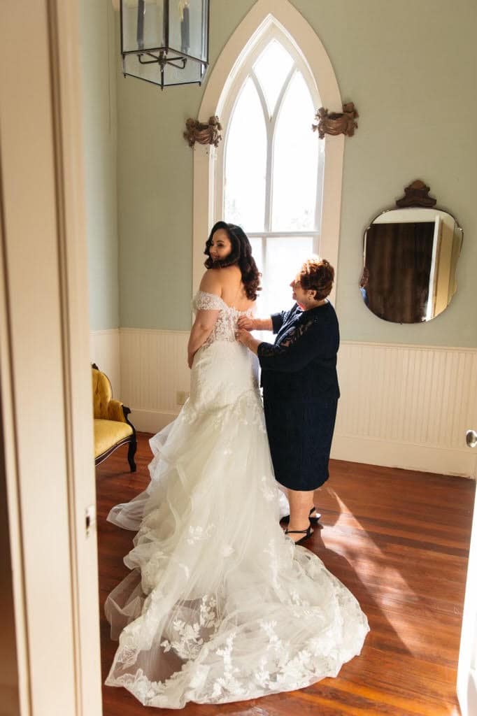 mother of the bride zipping her dress up as she gets ready at THE 1883 Historic Venue