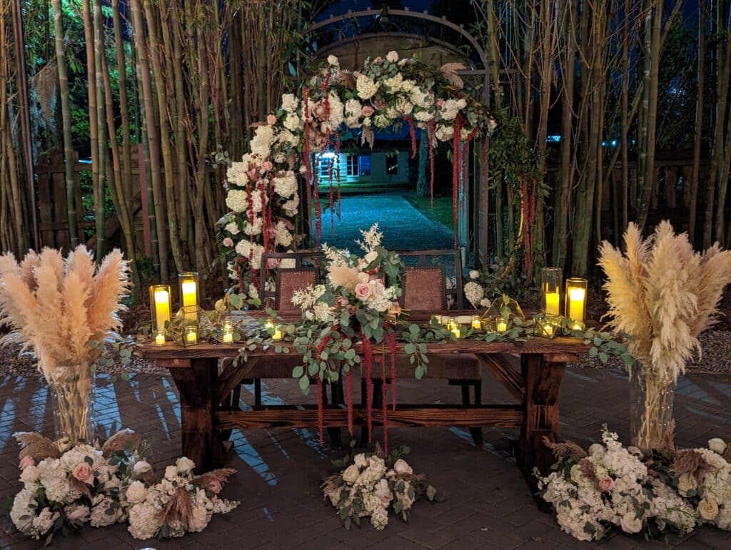 sprays of flowers and pompous grass and candles on wooden trellis table coordinated by Events by Rachel