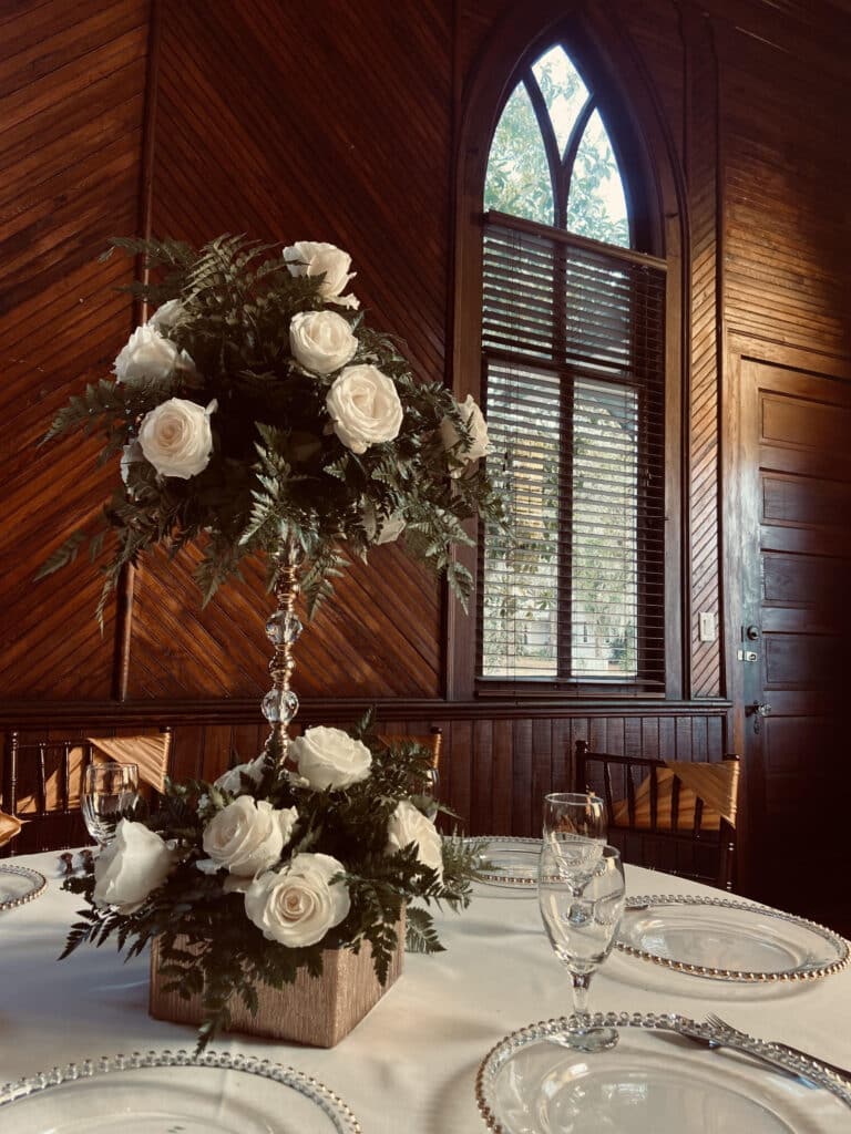 tall centerpieces in room with arched wooden window at THE 1883 Historic Venue