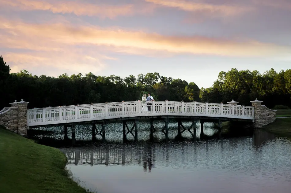 bride and groom kissing on bridge at St. Johns Golf & Country Club
