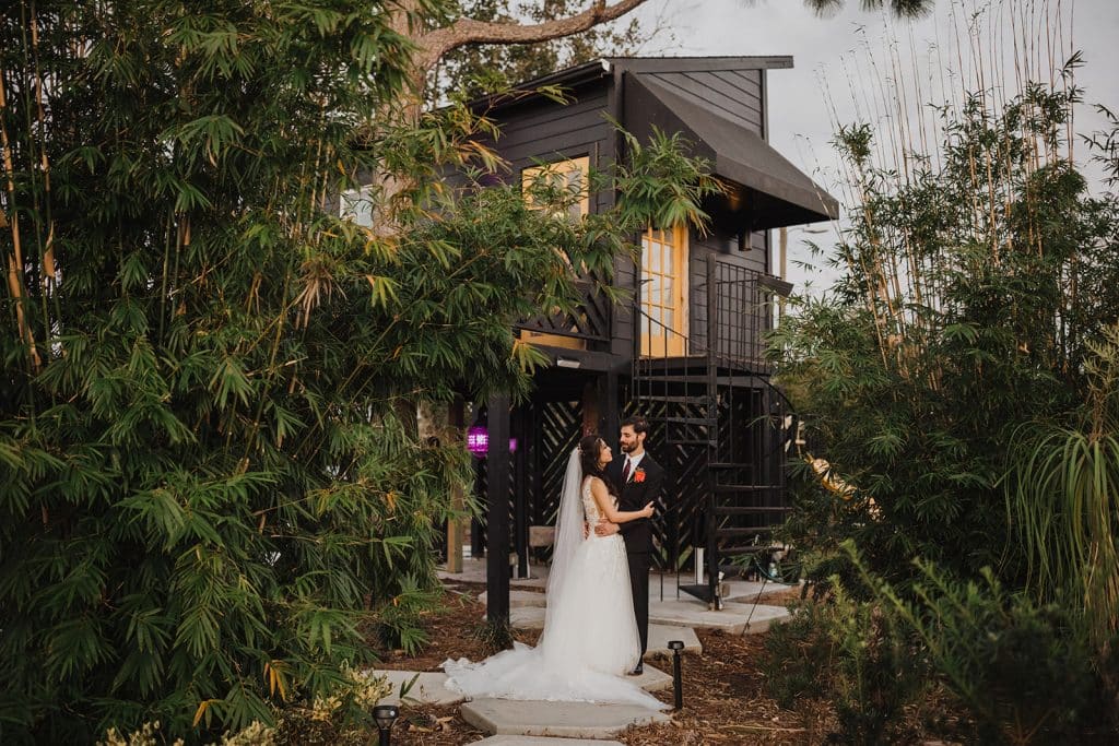 bride and groom in lush gardens with tree house at Wanderlust Okto
