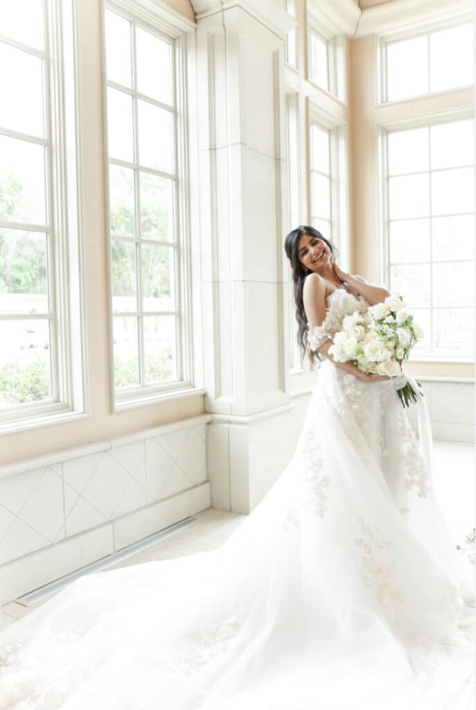 photo of bride in silhouette standing under sunlight streaming in large paned windows by Sylvia Santos Photography